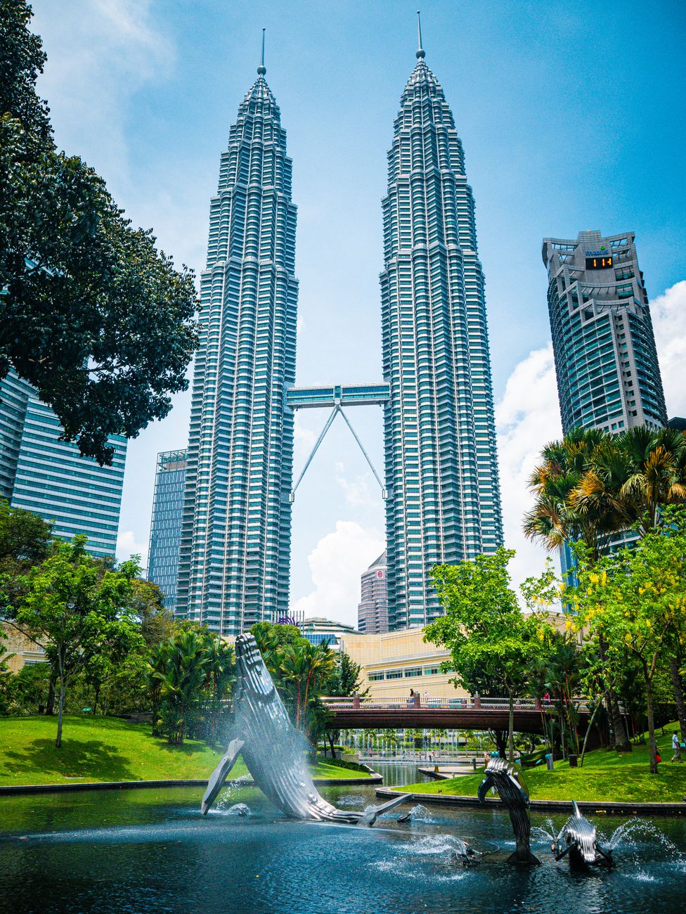 a low angle shot of petronas twin towers under the blue sky and white clouds
